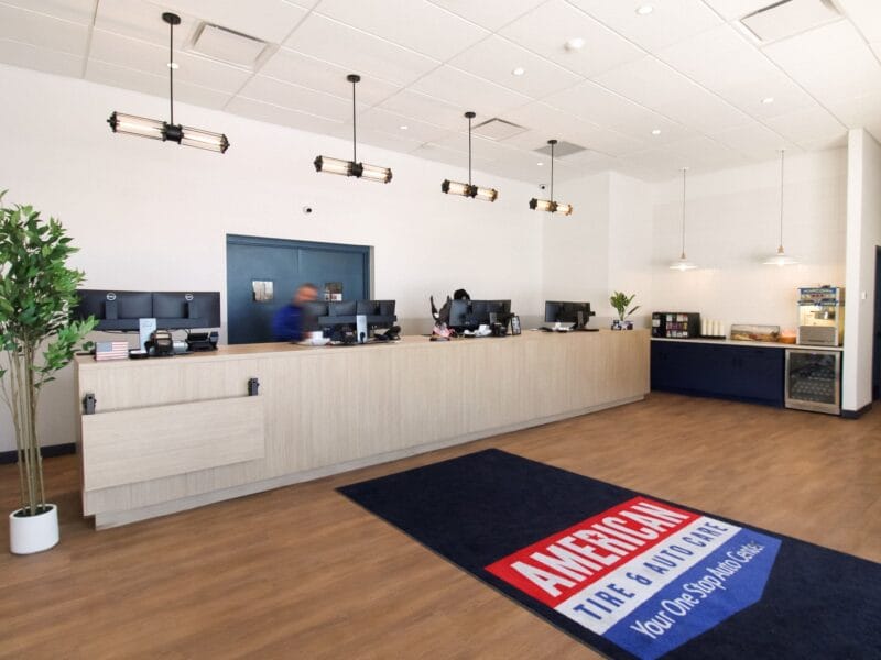 American Tire & Auto Care reception desk with branded entry mat and customer refreshment area