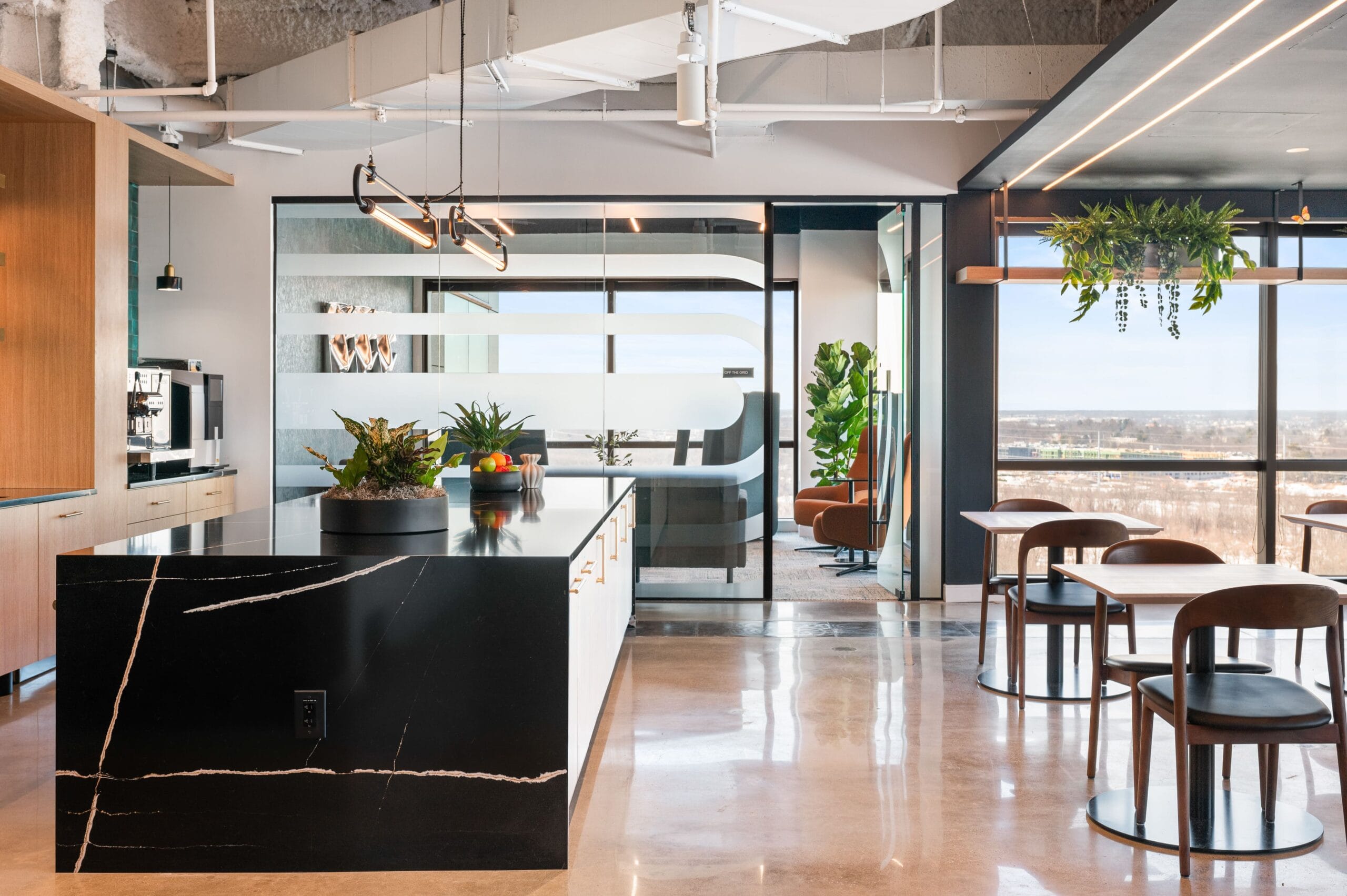Modern office café area in LS Power workplace retreat with kitchen island, seating, and glass meeting rooms in New Jersey